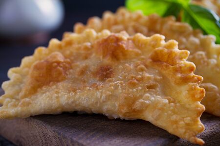 Chebureki - pan fried pies with meat and onions, served on wooden board. Fried-dough foodの写真素材