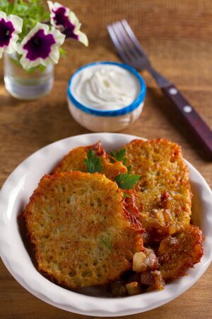 Potato pancakes with bacon and sour cream. Vegetable fritters, draniki - popular dish in many countriesの写真素材