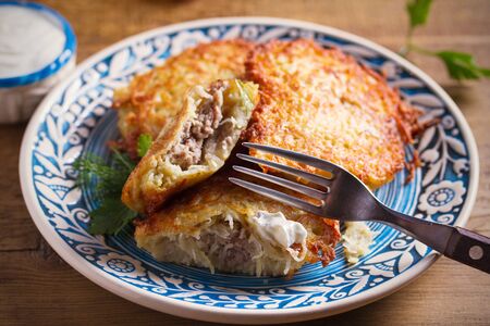 Potato Pancakes Filled With Meat. Vegetable fritters stuffed with meat on blue plate and sour cream or yogurtの写真素材