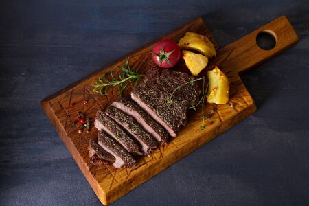 Grilled fillet beef steak with potatoes on serving board. View from above, top view