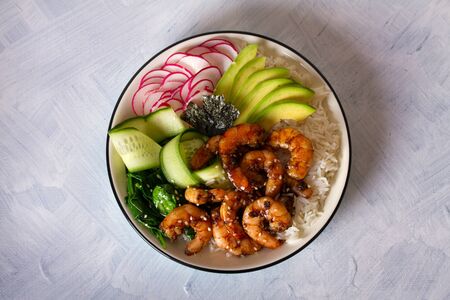 Honey soy shrimp rice bowl with spinach, radish cucumber, seaweed and avocado. View from above, top...