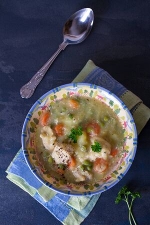 Bowl of chicken stew with vegetables on dark gray background.の写真素材