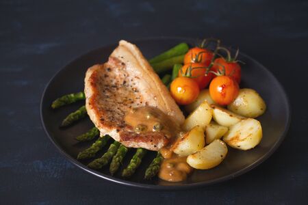 Roast pork chop with vegetables on black plate. horizontal imageの写真素材