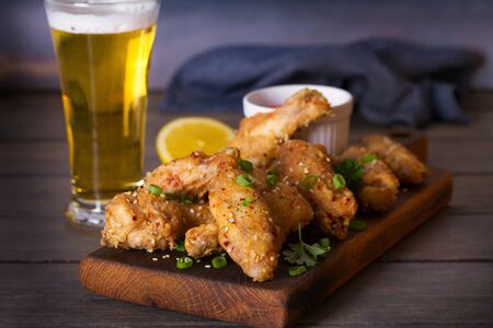 Chicken wings on serving board and glass of beerの写真素材