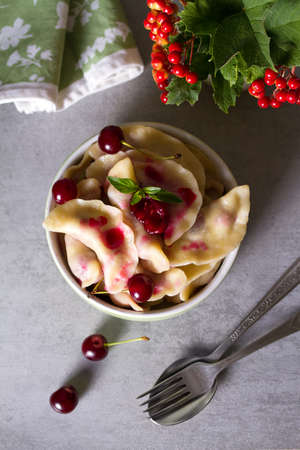 Dumplings, filled with cherries. Varenyky, vareniki, pierogi, pyrohy - dumplings with filling. View from above, top studio shotの写真素材