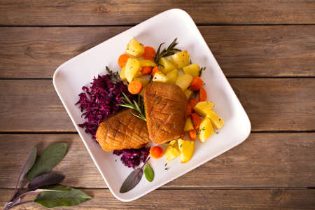 Roast duck breast fillets with potatoes, carrots and red cabbage. View from above, top studio shot
