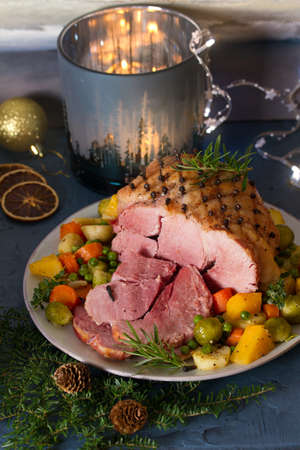 Roasted sliced ham with vegetables. Christmas decorations. New Year dinner tableの写真素材