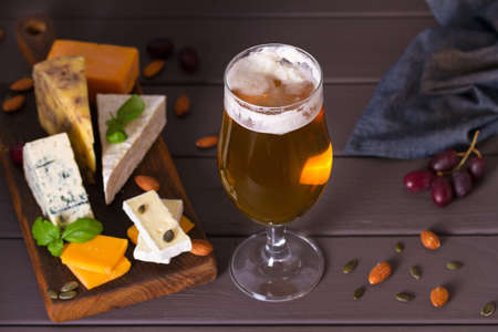 Beer and cheese. Glass of beer with cheese and walnuts. Ale and food concept