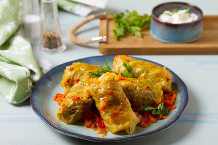 Stuffed cabbage leaves. Cabbage wraps or rolls. Chou farci, dolma, sarma, golubtsy or golabki on blue plate on green blue tableの写真素材