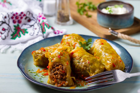 Stuffed cabbage leaves. Cabbage wraps or rolls. Chou farci, dolma, sarma, golubtsy or golabki on blue plate on green blue tableの写真素材