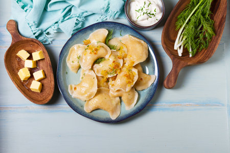 Dumplings with mashed potatoes filling. Varenyky, vareniki, pierogi, pyrohy - dumplings with filling on blue plate on green blue wood background. High angle viewの写真素材
