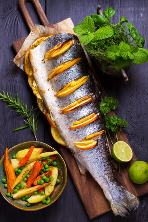 Roasted salmon with lemon, oranges and herbs. View from above, top studio shotの写真素材
