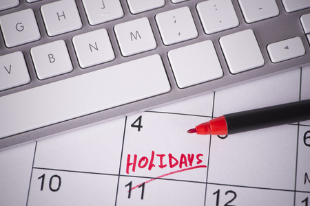 Calendar with holidays word written with a pen and computer keyboardの写真素材