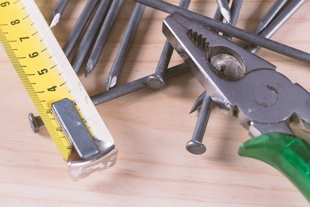 Nails, measuring tape and pliers on wooden table