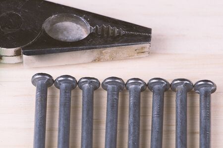 Nails aligned with pliers on woodの写真素材