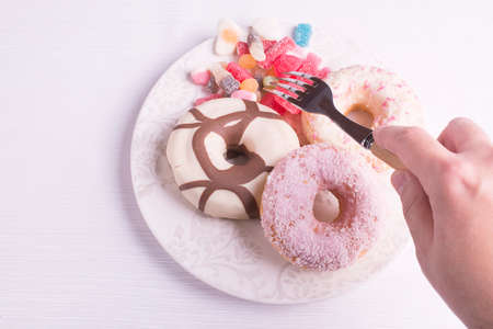 Hand clicking candies with donuts on a plate