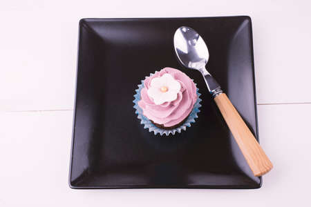 Cupcake and a spoon on a black plateの写真素材