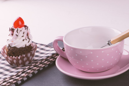 Cupcake with cup, plate and spoon and pink napkinの写真素材