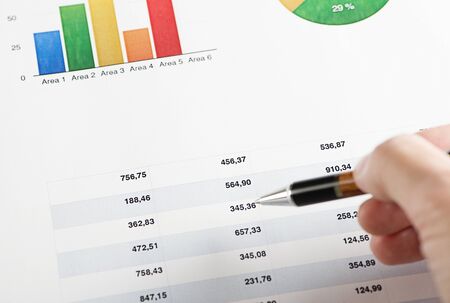 A hand with a pen pointing on finance colorful graphics