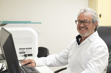 Portrait of senior smiling doctor working at computerの写真素材