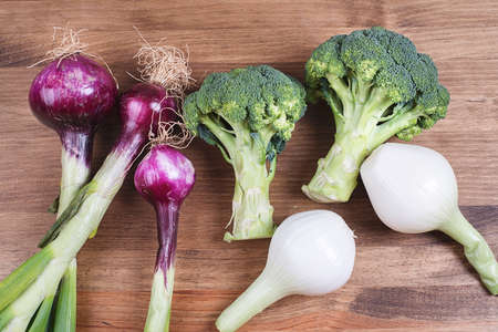 Different types of onion with raw broccoli and cabbage on plate in close-up