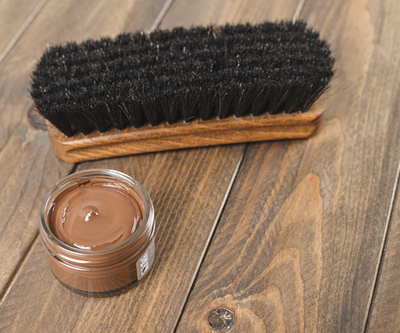 Close-up of brown dye and brush for cleaning shoes on wooden table Horizontal shoot.の写真素材