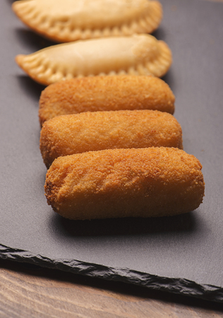 Several croquettes and small feet on slate plate. Vertical shoot.