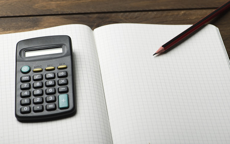 Calculator pen and notepad on brown wooden table.の写真素材
