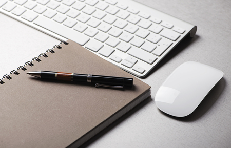 Ballpoint pen on a notebook next to a computer keyboard and a mouse. Technology.の写真素材