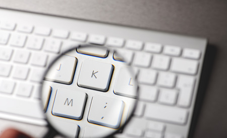 Magnifying glass over the letters of a keyboard over gray background. Technology.の写真素材