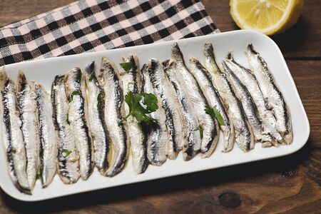 Plate of anchovies next to a lemon and a table napkin. Mediterranean diet.の写真素材