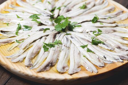 Close-up of anchovies with olive oil and vinegar on wooden plate. Healthy food.の写真素材