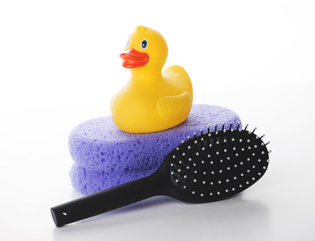 Yellow duckling on a lilac sponge next to a comb. Isolated. Horizontal shoot.の写真素材