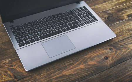 Laptop next to a flower on wooden table. Horizontal shoot.