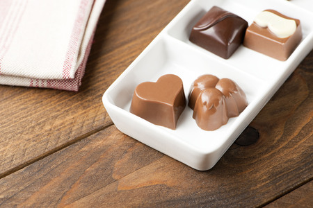 Chocolates with different shapes on white plate. Food.の写真素材