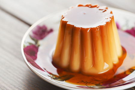 Horizontal studio shot of sweet flan dessert on a colorful plate.