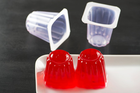 Strawberry jelly and empty containers on a black plate.