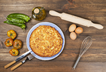 From above typical Spanish omeletteÂ with tomatoes, green peppers and oil in bottle on wooden table.の写真素材