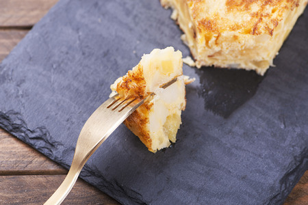 Fork with potato omelette over slate dish. Traditional Spanish food.の写真素材