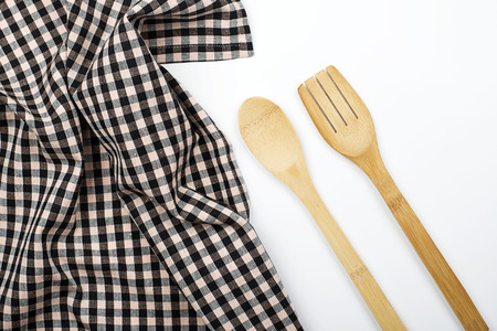 Background of plaid kitchen tablecloth and wooden cutlery on white background. Copy space. Kitchen.の写真素材