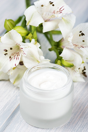 Flowers of lily next to a pot of cream for the skin. Vertical shoot.の写真素材