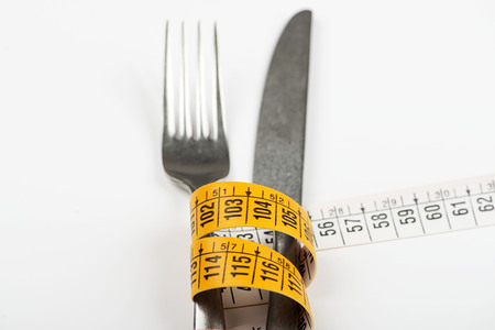 Tape measure on fork and knife. Concept of losing weight, diet.  の写真素材