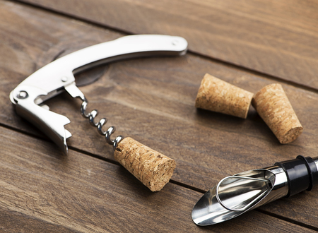Close-up of corkscrew on on wooden table next to several corks. Horizontal studio shot.の写真素材