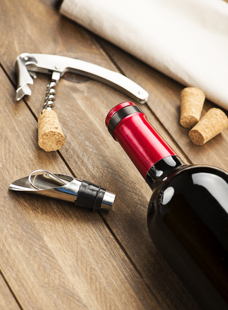 Corkscrew next to several corks, napkin and a bottle of wine. Vertical studio shot.の写真素材