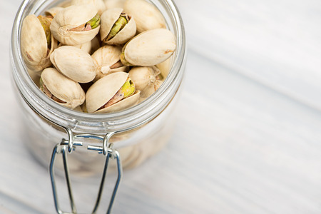 Close-up of pistachios in a glass bowl on wooden table.の写真素材