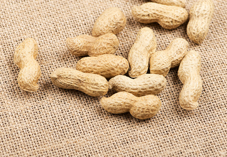 From above peanuts on canvas bag. Wooden background. Horizontal studio shot.