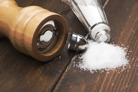 Close-up shot of pair of wooden salts and pepper next to a napkin on wooden table.の写真素材