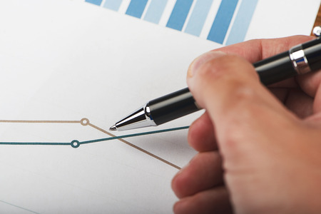 Close-up of business graphs and a male hand with a pen. Analysis of financial data.の写真素材