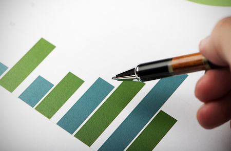 Close-up of business graphs and a male hand with a pen.