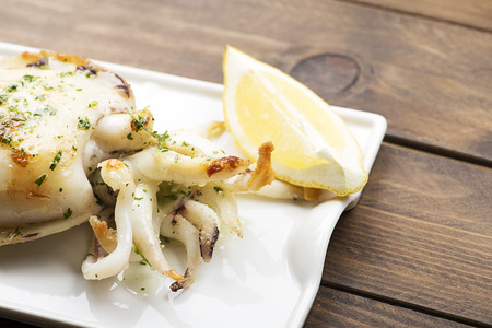Cuttlefish with garlic and parsley and lemon on wooden table.の写真素材